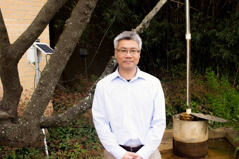 Frank Tsai posing by water well.