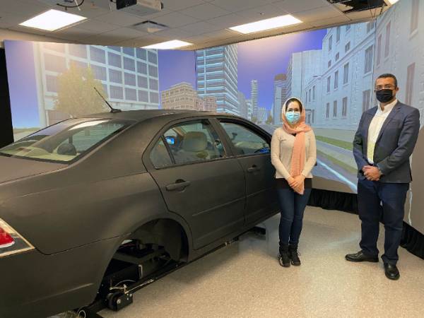 Hassan and grad student standing by car in lab