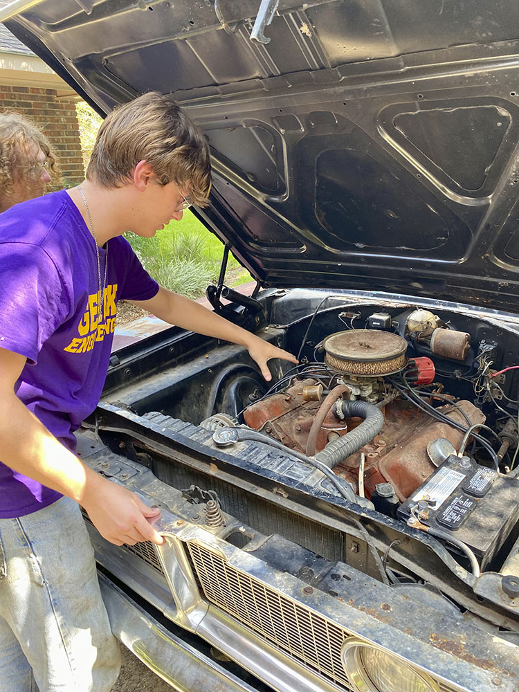 Ethan Songne works on the car engine