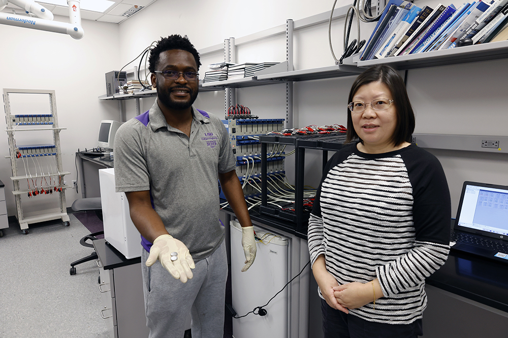 Image of Ying Wang in her lab with student holding battery.