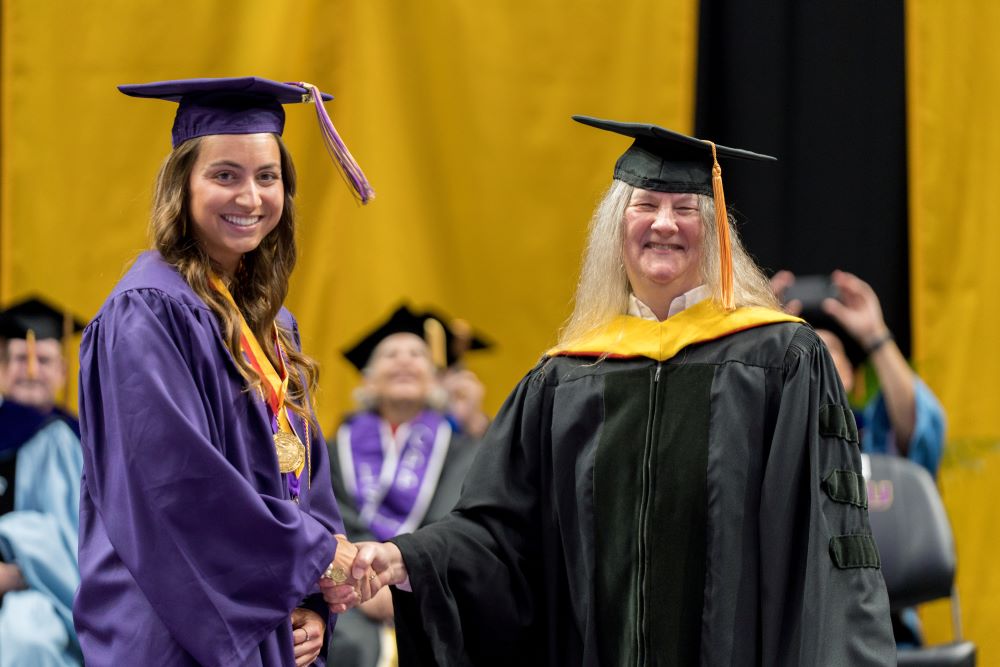 Alexis Nibert shakes hands with the dean at commencement ceremony