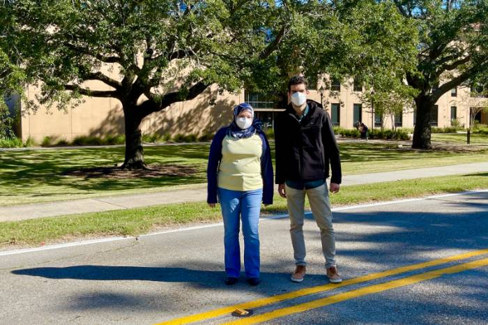 Man and woman wearing masks standing in road