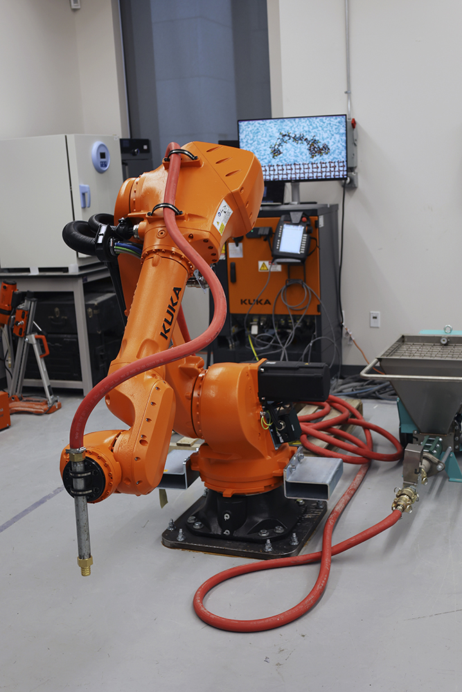 A large orange robot arm used for 3D printing concrete
