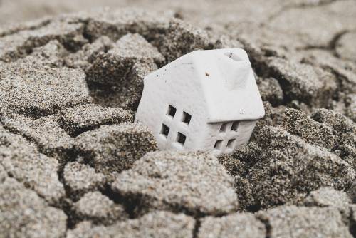 Small model of house sinking in dirt