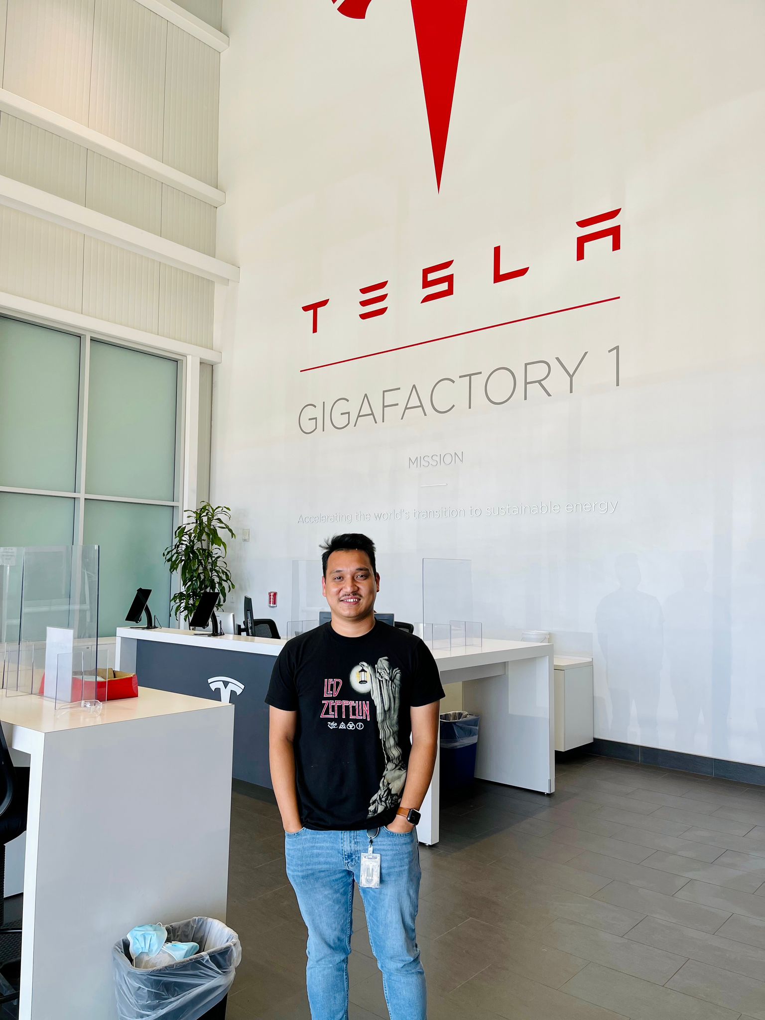 Min Pun stands in a Tesla factory lobby