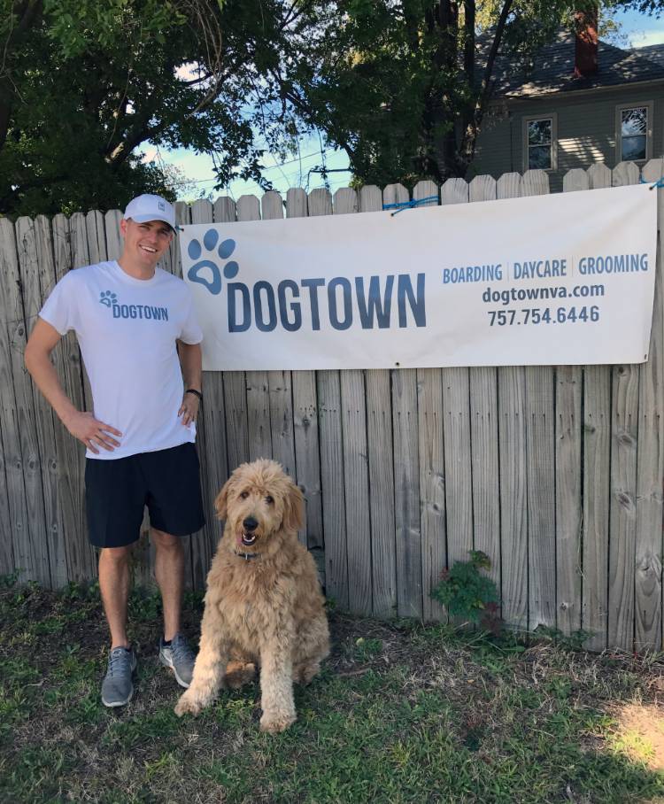 Sam Woomer posing with goldendoodle dog