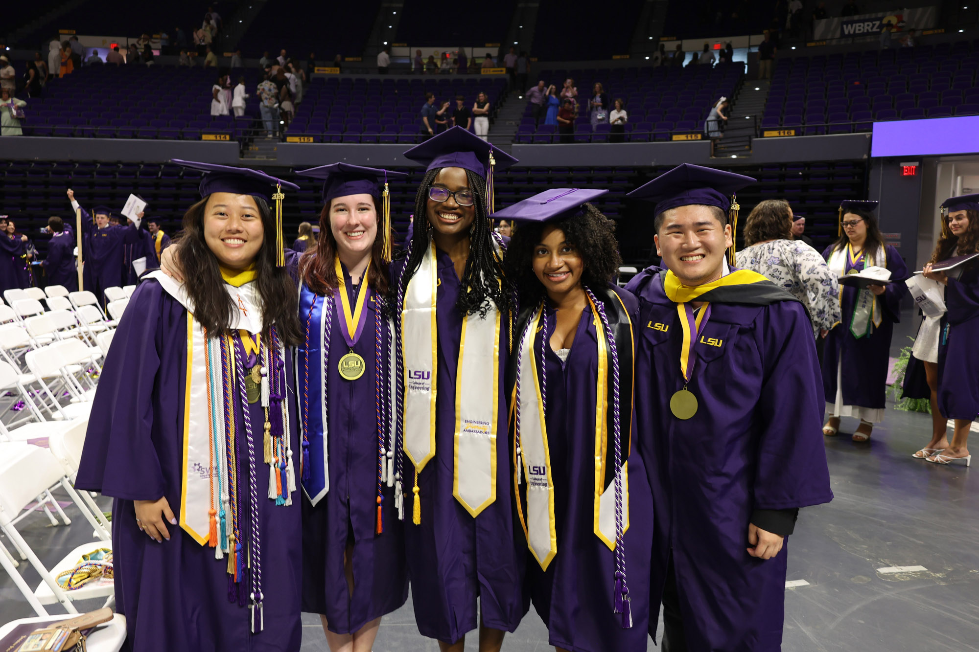 A group of five students pose for a picture after graduation ceremony in the PMAC