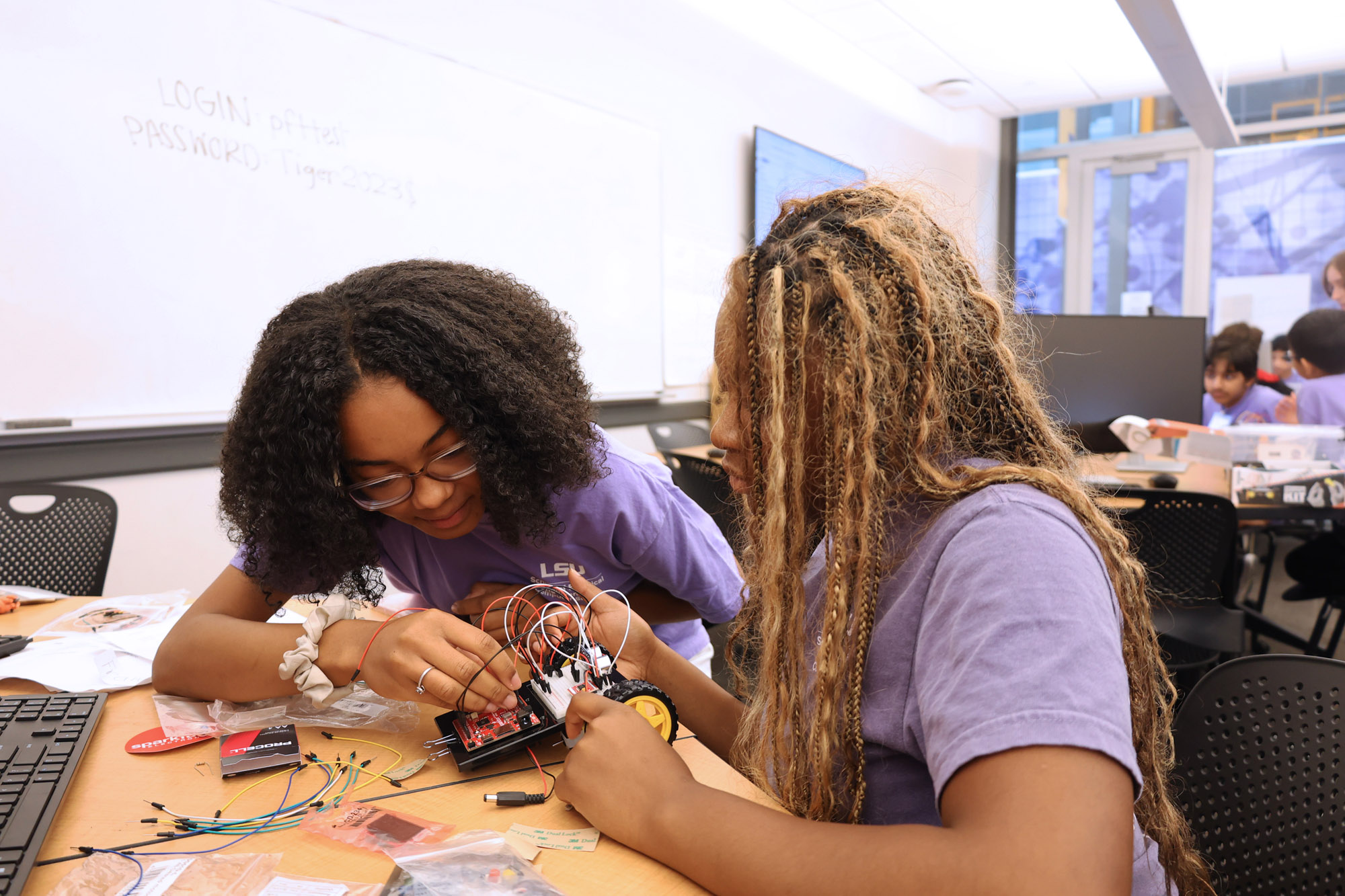 Two female students work together on wiring a car