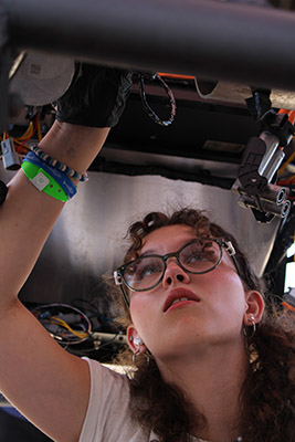 Female student working from underneath the car