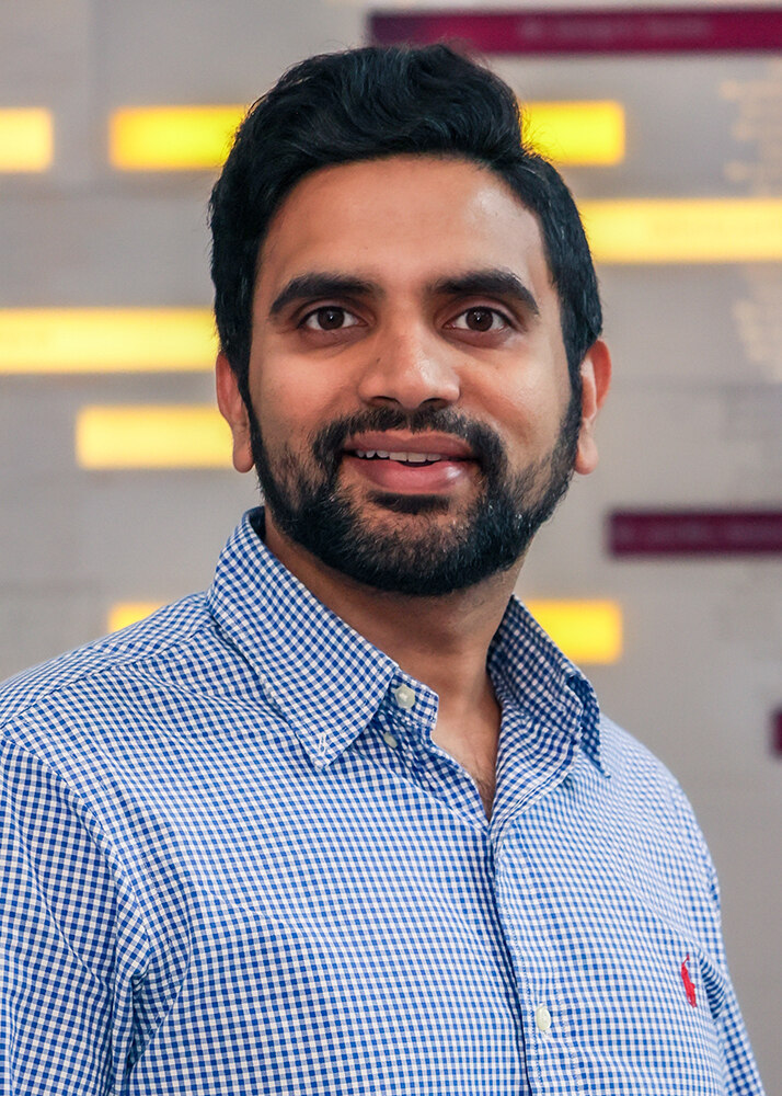 Portrait headshot of Dr. Phani Vadrevu in professional dress clothes in front of a soft-focused background of colorful streaked lights.