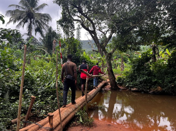 Crew members crossing the Nsakye River during the pedestrian survey.