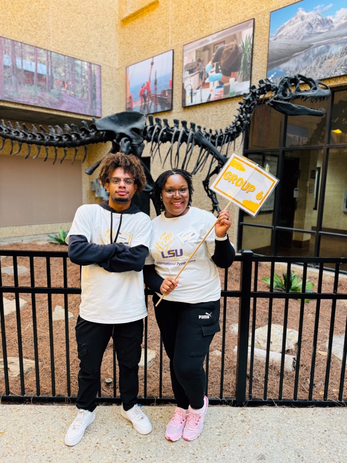 two students in LSU tshirts smile with a sign that says "group 6"