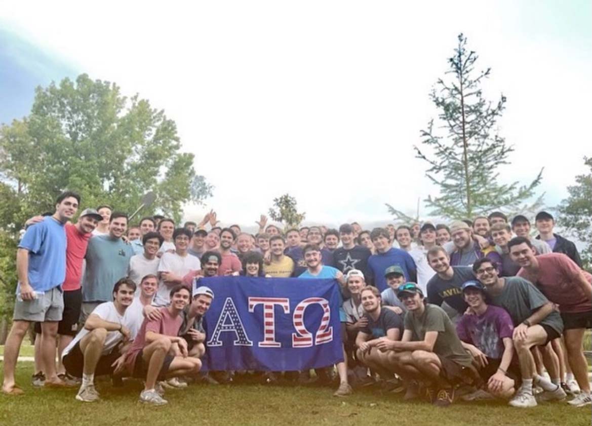 alpha tau omega members pose with banner