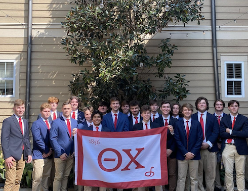 theta chi members holding their fraternity flag