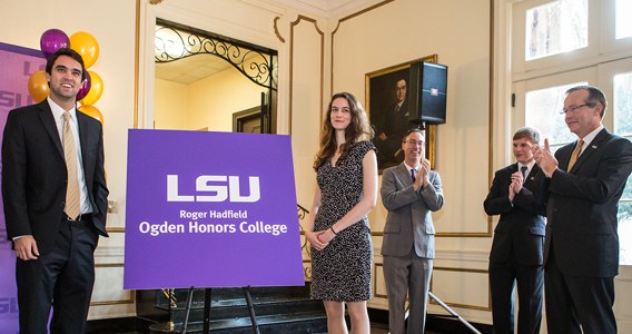 Man and a woman standing in front of the new Roger Hadfield Ogden Honors College logo