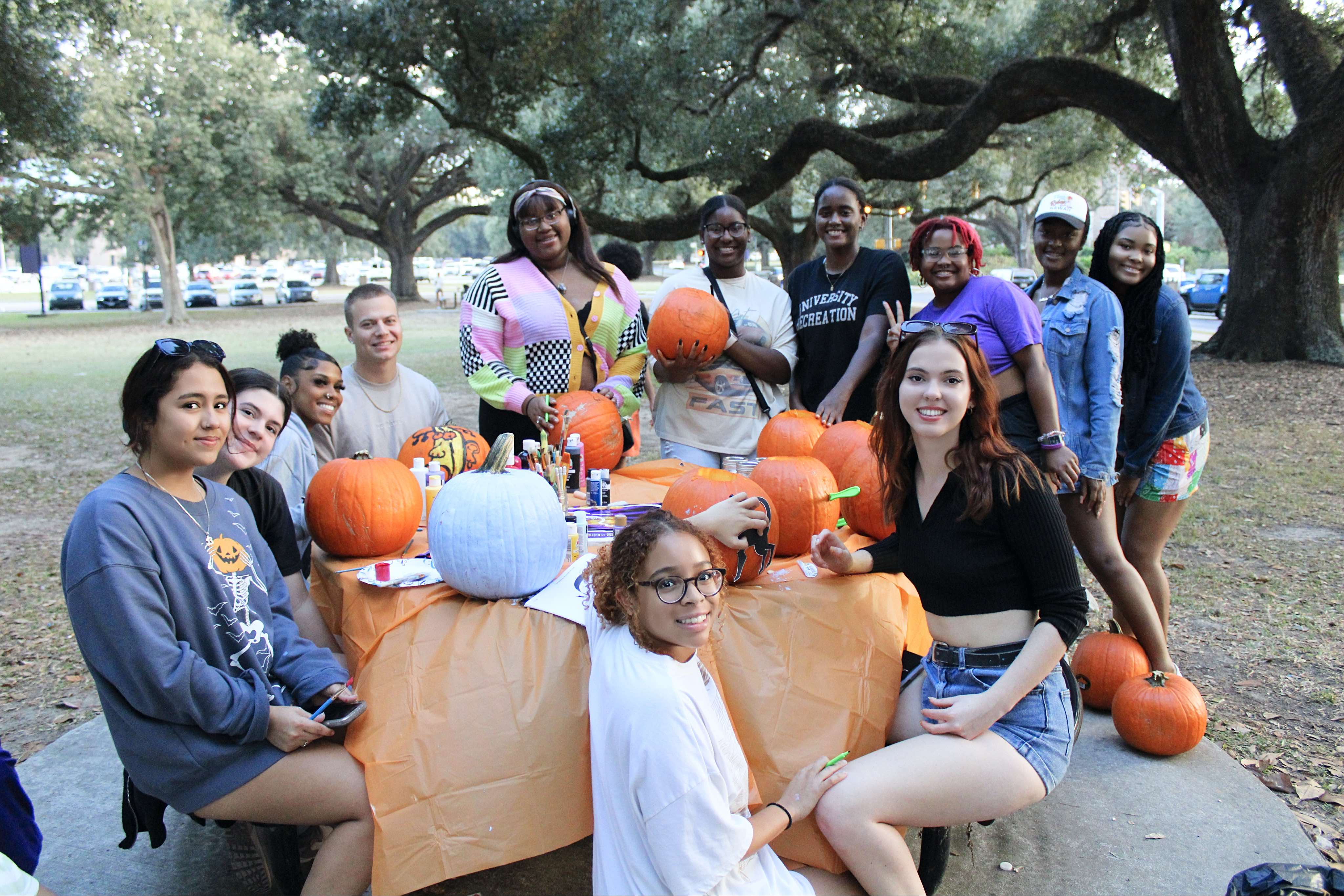 Students posing for a photo as they paint pumpkins.
