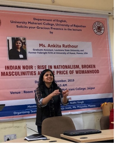 Ankita speaks animatedly from behind conference table. The poster behind her reads, "Indian Noir: Rise in Nationalism, Broken Masculinities and the Price of Womanhood.