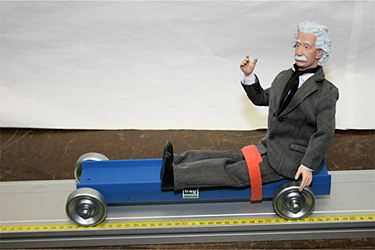 photo:  Einstein action figure riding on cart with/without seatbelt - hits wall