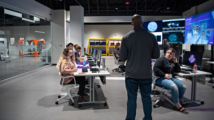 a teacher talks to students in a cybersecurity lab