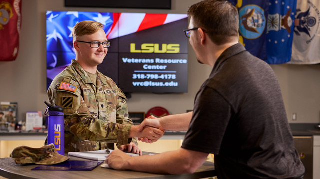 Student in uniform shakes hands with a visitor at the LSUS Veterans Resource Center
