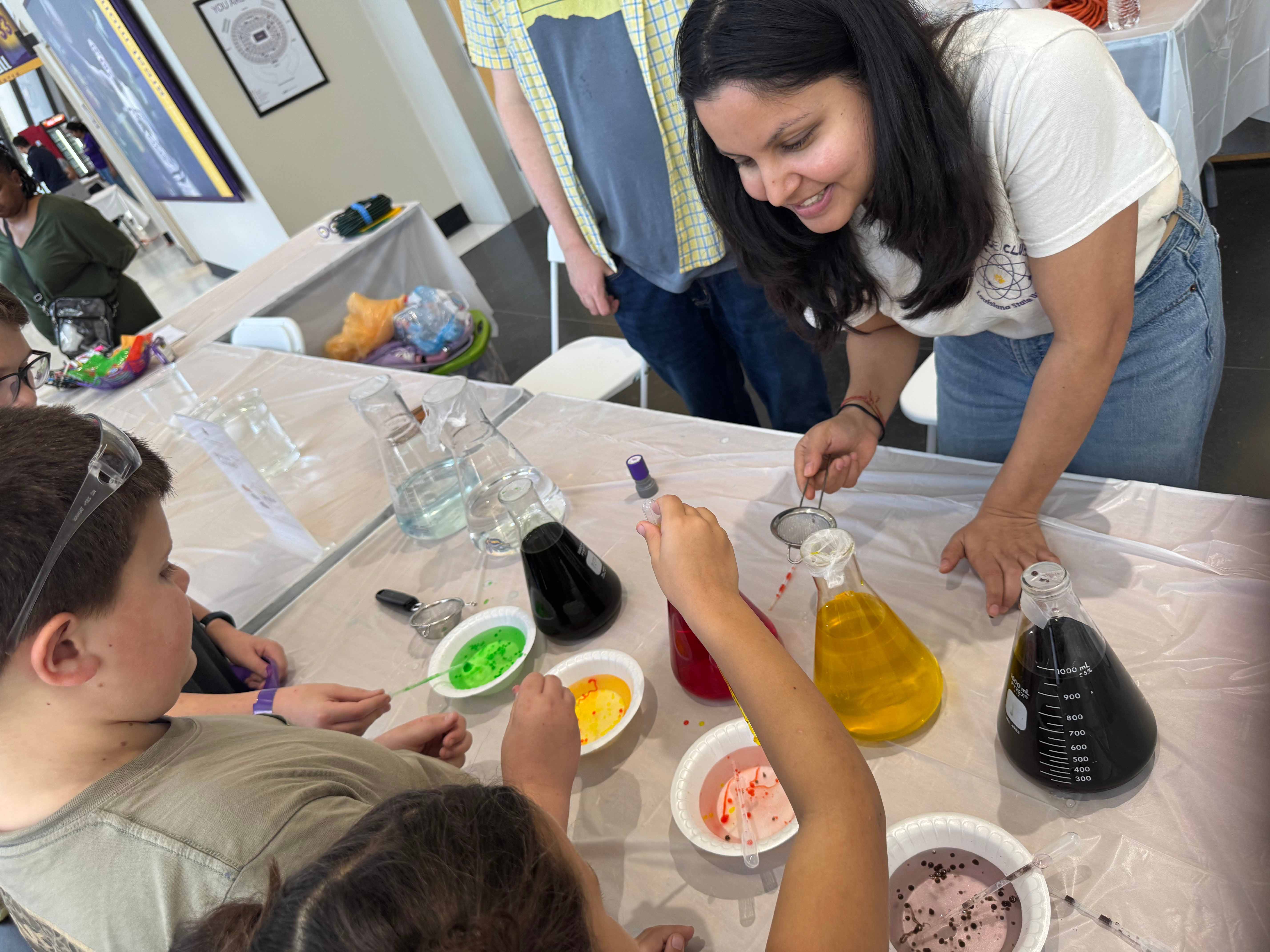 Super Science Saturday woman showing kids containers of colored liquid