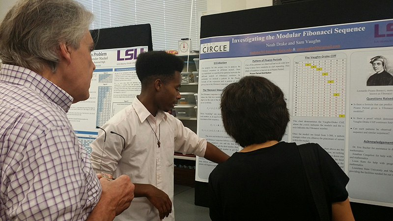 Math Cirlce student showing his poster to two LSU faculty members.