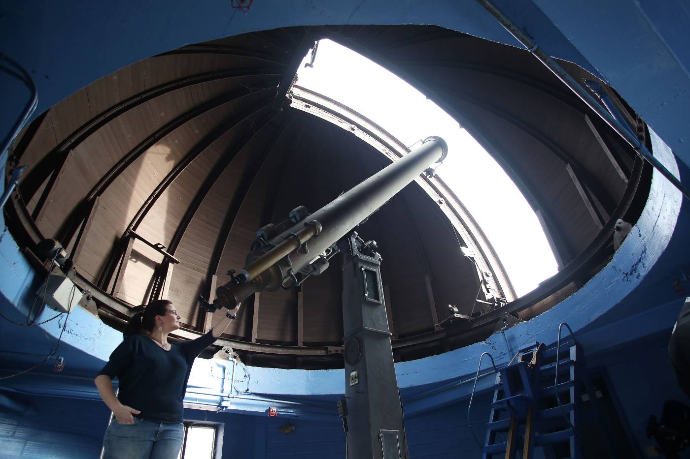 Astronomer looking through the lens inside of an large telescope an observatory