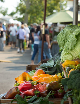 Photo of a farmers market with lettuce and peppers in the foreground