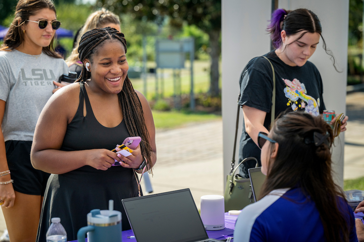 student discussing with staff at a table during an event on campus